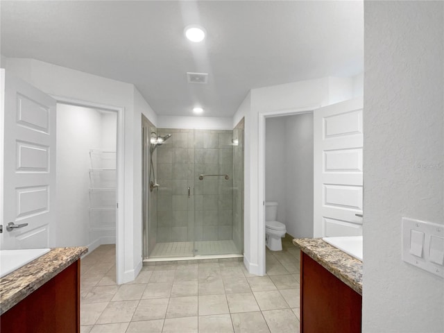 bathroom featuring tile patterned floors, vanity, toilet, and a shower with door