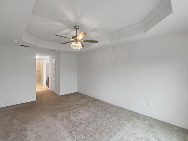 unfurnished room with a raised ceiling, ceiling fan, crown molding, and carpet floors