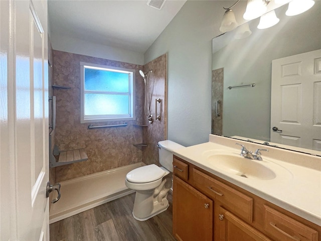 bathroom with vanity, vaulted ceiling, hardwood / wood-style flooring, toilet, and tiled shower