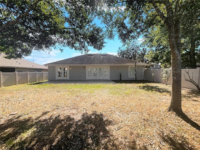 rear view of property with a lawn, a patio area, and french doors