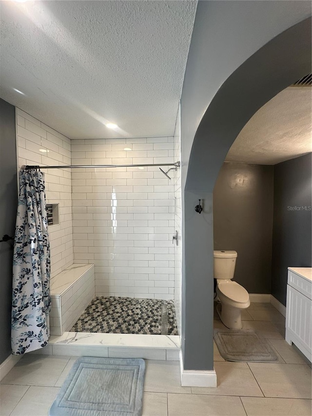 bathroom featuring tile patterned floors, a shower with curtain, toilet, a textured ceiling, and vanity