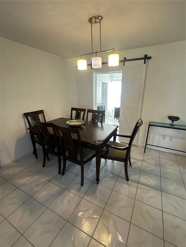 dining space with a barn door and tile patterned floors