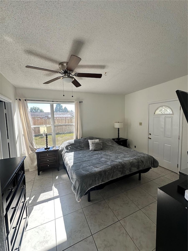 tiled bedroom featuring ceiling fan and a textured ceiling