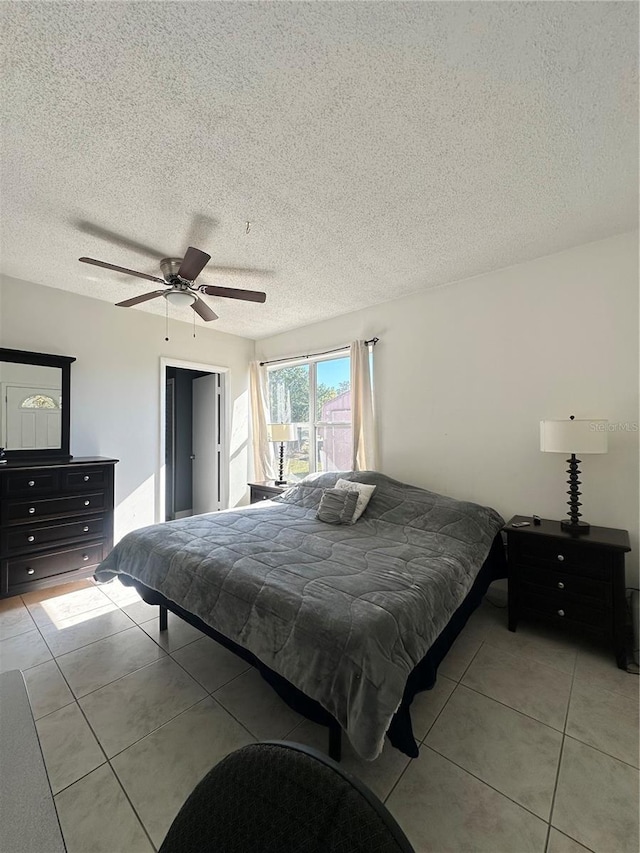 tiled bedroom with ceiling fan and a textured ceiling