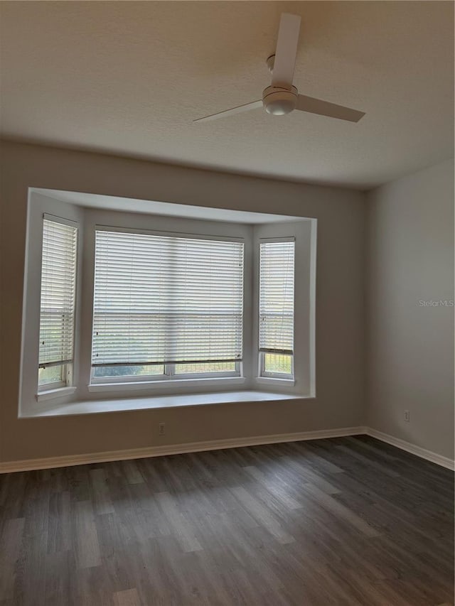 unfurnished room featuring a wealth of natural light, dark hardwood / wood-style flooring, and ceiling fan