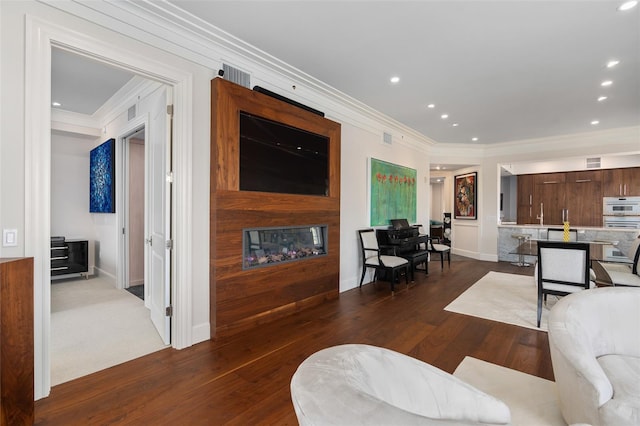 living area with recessed lighting, ornamental molding, a fireplace, and dark wood-style flooring