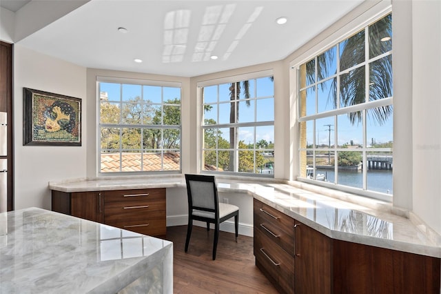 office area featuring built in desk, recessed lighting, dark wood-type flooring, and a water view