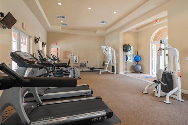 gym with visible vents, recessed lighting, a raised ceiling, and baseboards