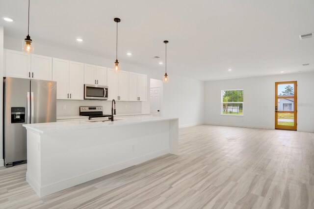 kitchen featuring a center island with sink, stainless steel appliances, and light hardwood / wood-style flooring