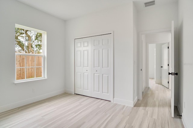 unfurnished bedroom with light hardwood / wood-style flooring and a closet