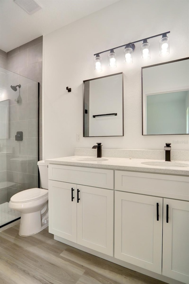 bathroom with hardwood / wood-style flooring, vanity, toilet, and an enclosed shower