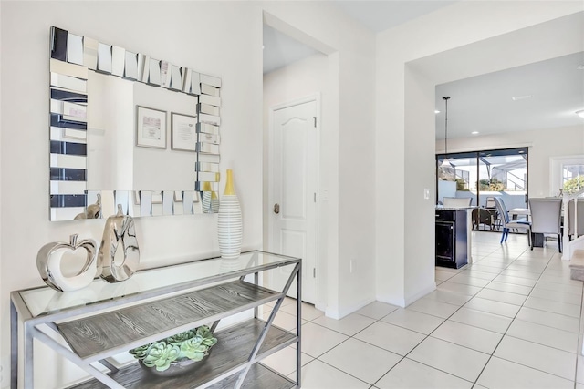 hallway with light tile patterned floors and an inviting chandelier