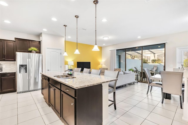 kitchen with hanging light fixtures, sink, appliances with stainless steel finishes, dark brown cabinetry, and a breakfast bar area