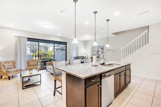 kitchen with light stone countertops, a breakfast bar, pendant lighting, a center island with sink, and dishwasher