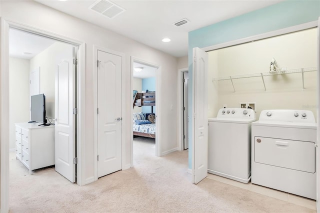 clothes washing area featuring light colored carpet and washing machine and clothes dryer