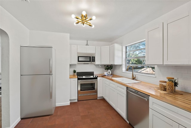 kitchen featuring stainless steel appliances, sink, wooden counters, and white cabinets