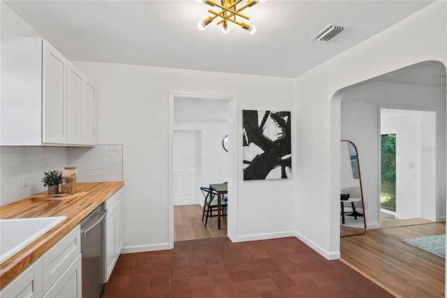 kitchen with dishwasher, white cabinets, wood counters, and decorative backsplash