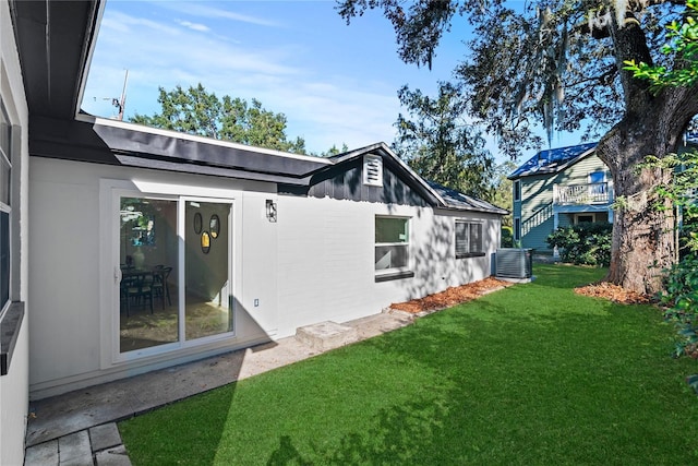 rear view of property with central AC and a lawn