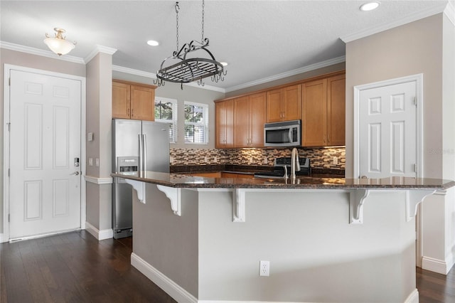 kitchen with dark hardwood / wood-style floors, stainless steel appliances, a breakfast bar area, and an island with sink