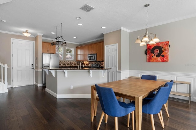 dining space with dark hardwood / wood-style flooring, ornamental molding, a textured ceiling, sink, and a notable chandelier