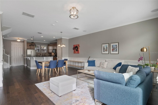 living room with ornamental molding, dark hardwood / wood-style flooring, and a notable chandelier