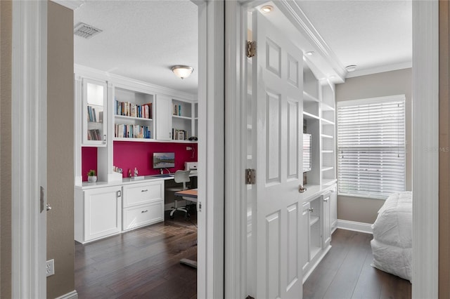 corridor featuring dark hardwood / wood-style floors, ornamental molding, and a textured ceiling