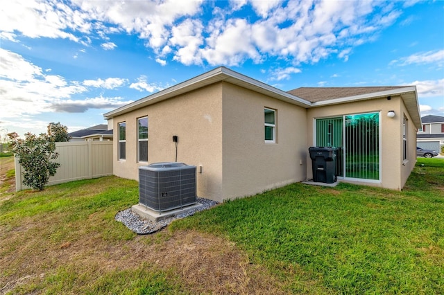 rear view of house with a yard and central AC