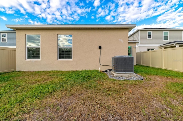 rear view of house featuring a yard and central air condition unit