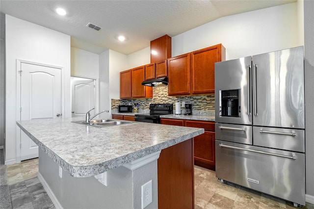 kitchen with black appliances, a center island with sink, sink, a textured ceiling, and tasteful backsplash