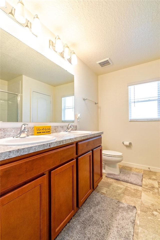 bathroom featuring vanity, a shower with shower door, a textured ceiling, and toilet