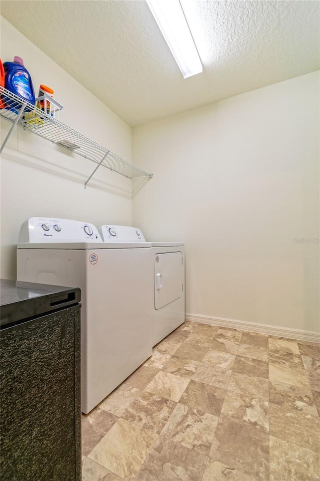 laundry area featuring a textured ceiling and washing machine and clothes dryer