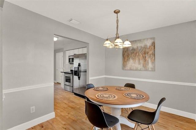 dining room with light wood-type flooring and a chandelier