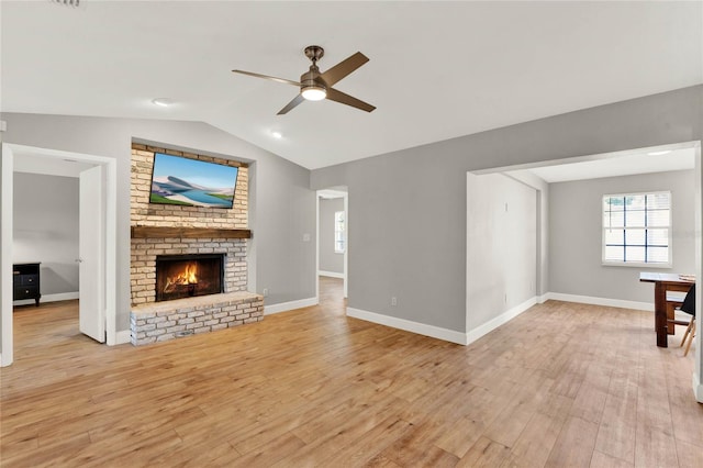 unfurnished living room with ceiling fan, a fireplace, light hardwood / wood-style floors, and lofted ceiling