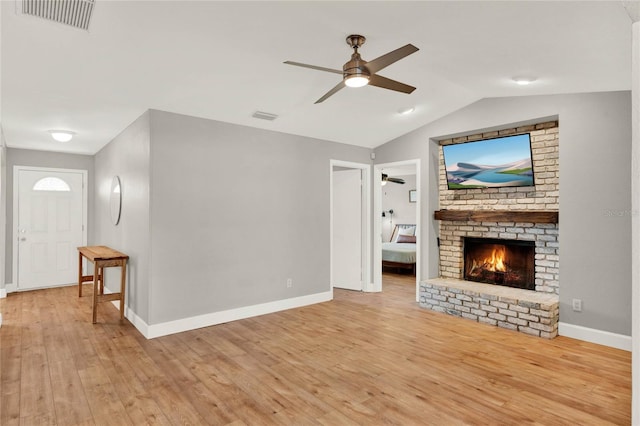 living room with ceiling fan, light hardwood / wood-style floors, lofted ceiling, and a fireplace