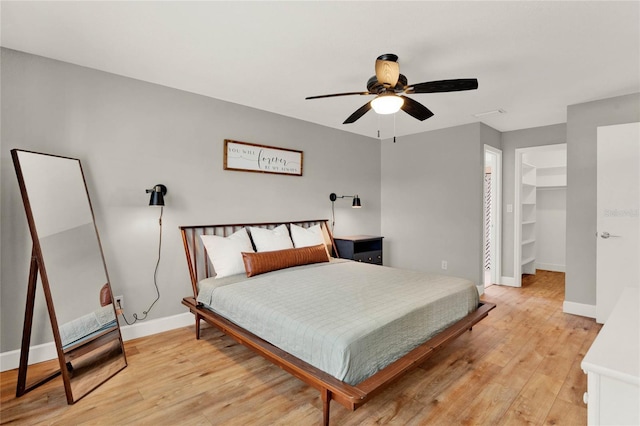 bedroom with a closet, light hardwood / wood-style floors, a spacious closet, and ceiling fan