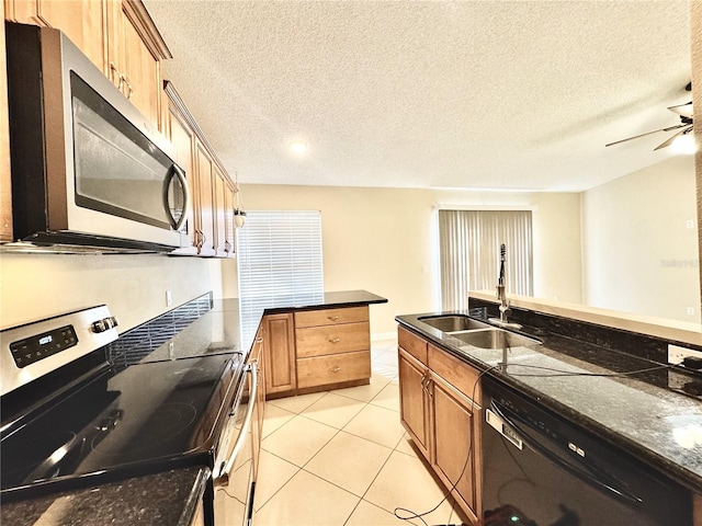 kitchen featuring light tile patterned flooring, sink, appliances with stainless steel finishes, and dark stone counters