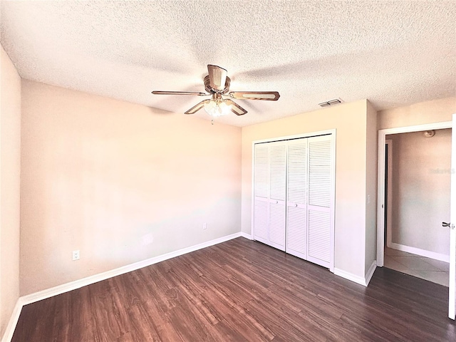 unfurnished bedroom with a textured ceiling, dark hardwood / wood-style flooring, a closet, and ceiling fan