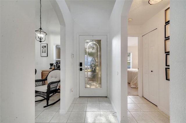 tiled entryway with a notable chandelier