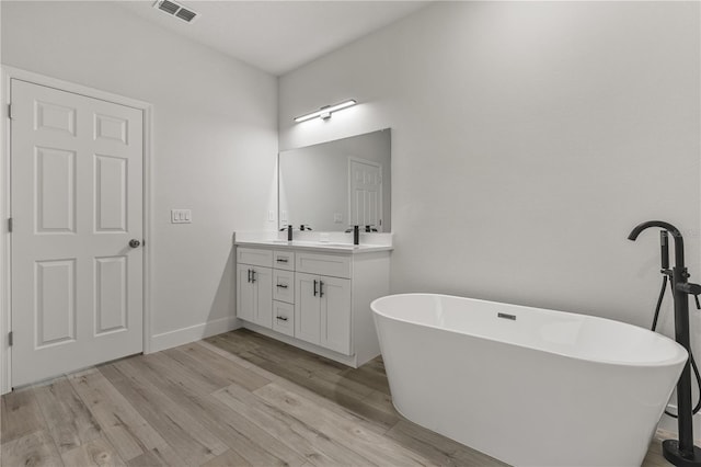 bathroom with a tub, hardwood / wood-style floors, and vanity