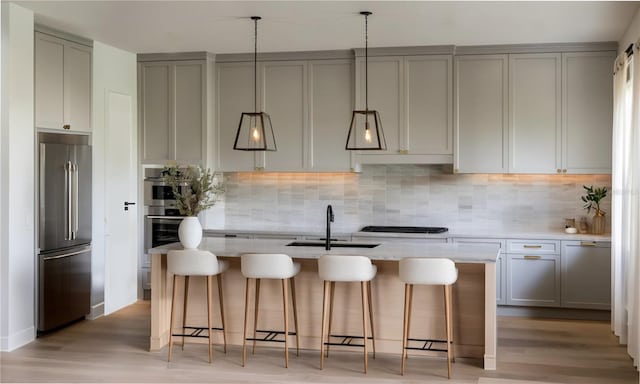 kitchen featuring gray cabinets, sink, stainless steel appliances, and an island with sink