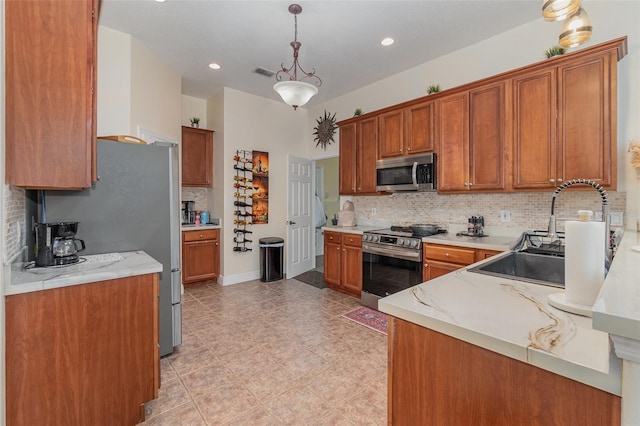 kitchen with stainless steel appliances, hanging light fixtures, light stone countertops, sink, and backsplash