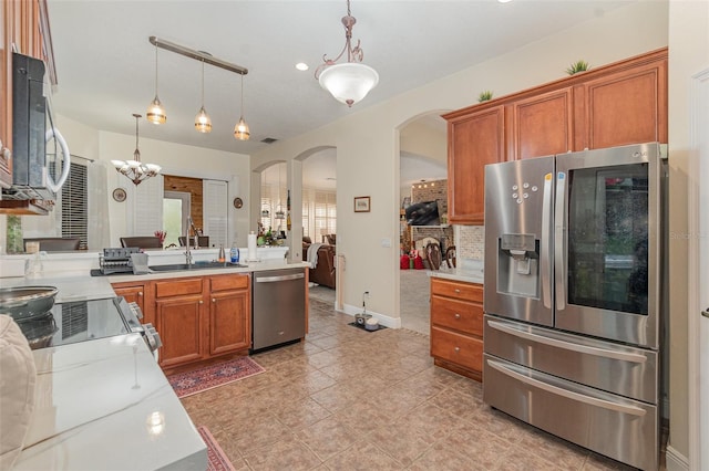 kitchen with light stone countertops, hanging light fixtures, stainless steel appliances, a notable chandelier, and sink