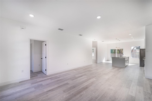 2416 SW 158th Pl, Ocala, FL 34473 - unfurnished living room with a sink, light wood-type flooring, recessed lighting, baseboards, and a chandelier