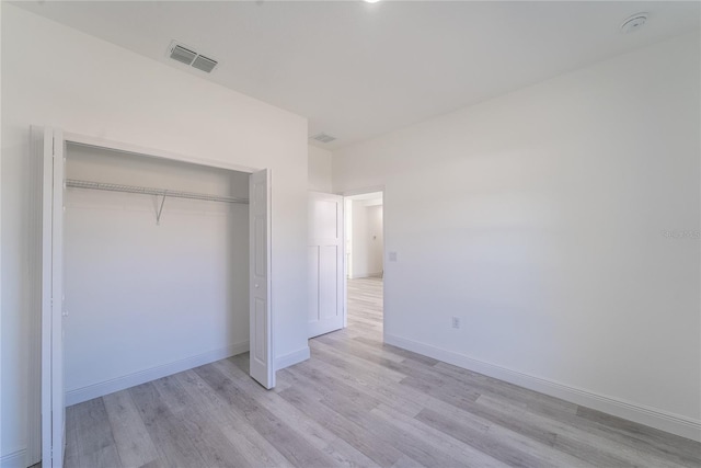 unfurnished bedroom with light wood-type flooring and a closet