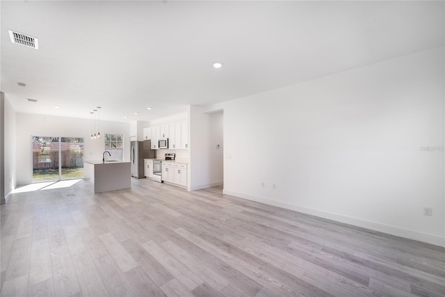 unfurnished living room with light wood-type flooring and sink