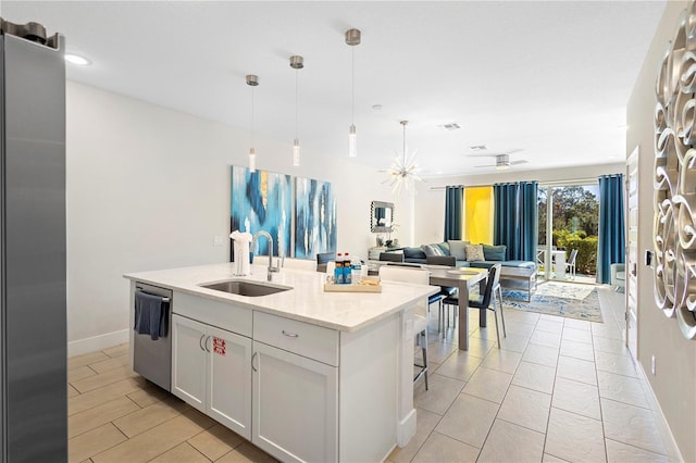 kitchen featuring appliances with stainless steel finishes, a kitchen island with sink, sink, decorative light fixtures, and white cabinetry