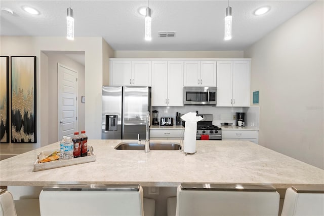 kitchen featuring sink, an island with sink, stainless steel appliances, and decorative light fixtures