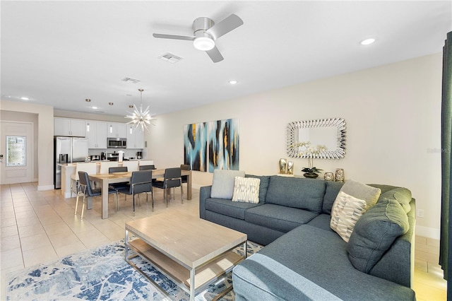 tiled living room featuring ceiling fan with notable chandelier