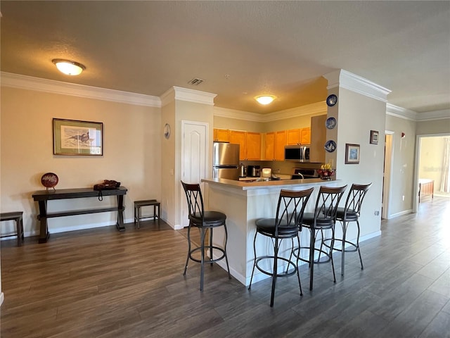 kitchen featuring dark hardwood / wood-style floors, a kitchen breakfast bar, kitchen peninsula, and stainless steel appliances