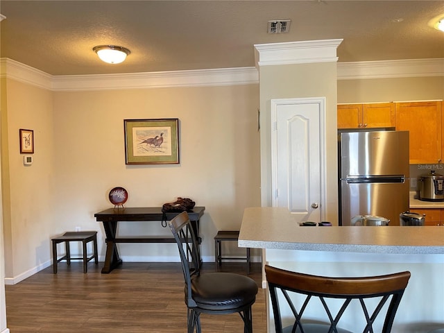 kitchen featuring a textured ceiling, stainless steel fridge, crown molding, and dark wood-type flooring